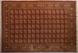 A pure wool Bokhara carpet with repeating gul motifs on burgundy ground within stylised geometric