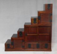 A Chinese hardwood three section cabinet fitted with an arrangement of identical cupboards to each