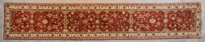 A Ziegler runner with allover scrolling floral design on a deep red field. L.335x60cm