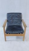 A mid century vintage teak framed armchair with black leather seat and back cushions. 77x70cm