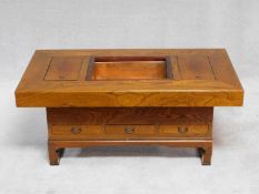 A Chinese elm low table fitted with lift out copper ice troughs and three base drawers on block