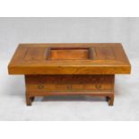 A Chinese elm low table fitted with lift out copper ice troughs and three base drawers on block