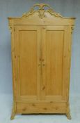 A 19th century North European pitch pine hall cupboard with ornately carved cresting above a pair of