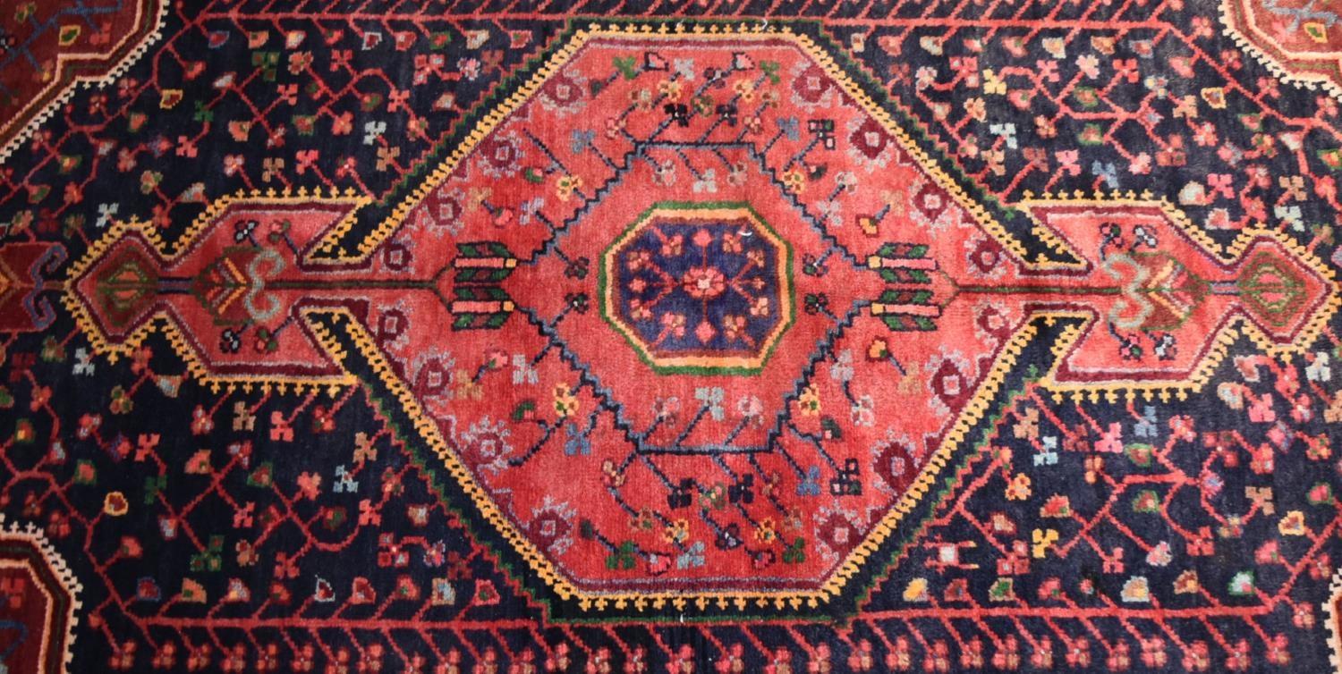 A Persian Nahavand rug with central pendant medallion on a rouge field with meandering vine - Image 2 of 4