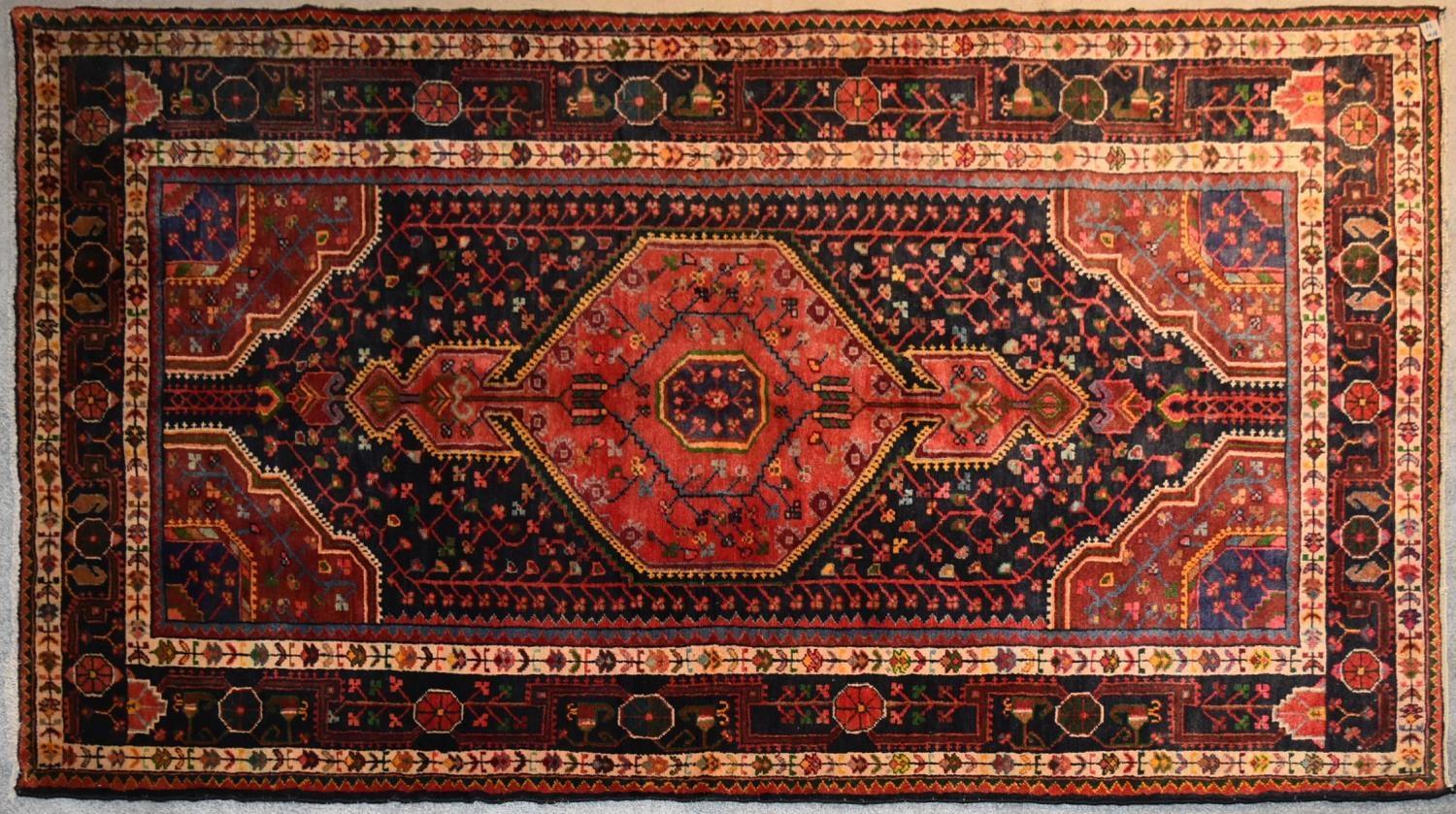 A Persian Nahavand rug with central pendant medallion on a rouge field with meandering vine