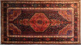 A Persian Nahavand rug with central pendant medallion on a rouge field with meandering vine