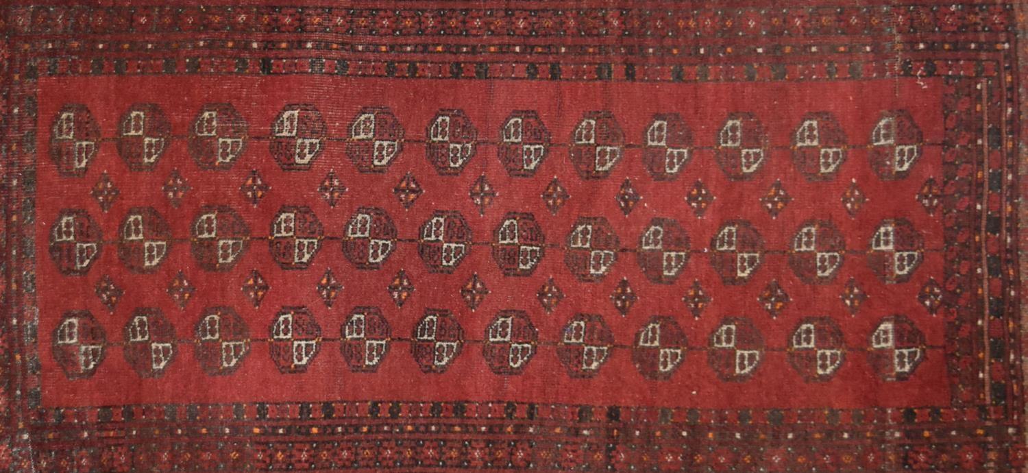 An Afghan Bokhara rug with repeating elephant's pad motifs on crimson ground within stylised multi - Image 2 of 4