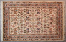 An Indian rug with meandering and scrolling vine decoration across the field on a beige ground