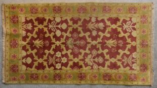 An Indian Moughal design rug with floral and foliate decoration within lotus leaf borders. L.