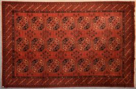 An Afghan Bokhara carpet with repeating tauk nuska gul design on a burgundy field within geometric