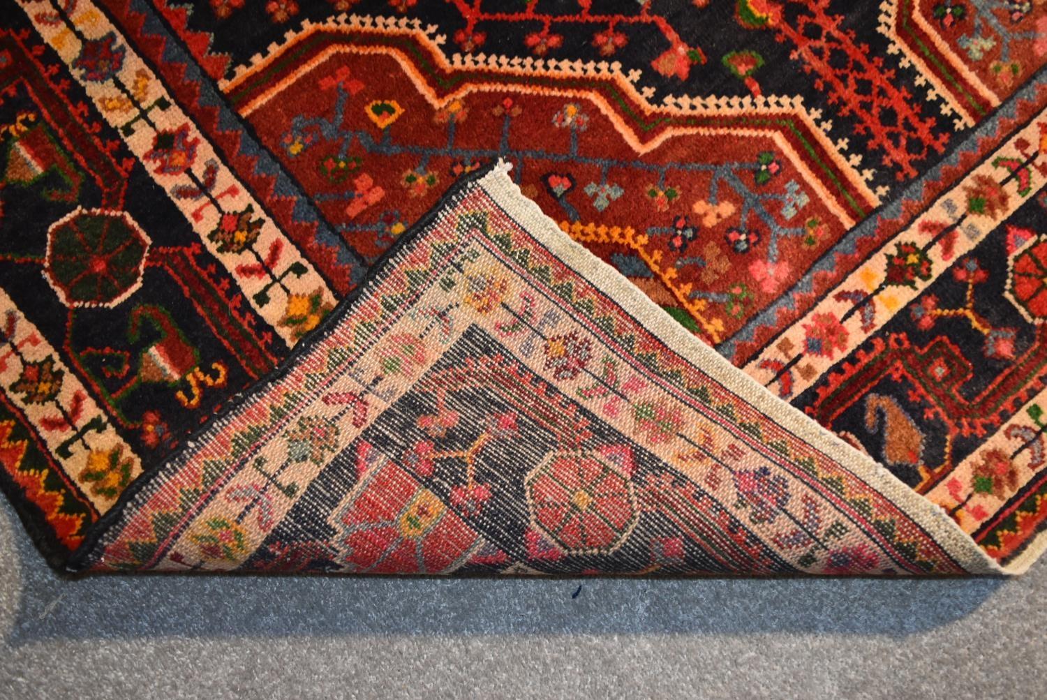 A Persian Nahavand rug with central pendant medallion on a rouge field with meandering vine - Image 4 of 4