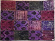 A flat weave rug with patchwork design in various purple hues. L.237x175cm