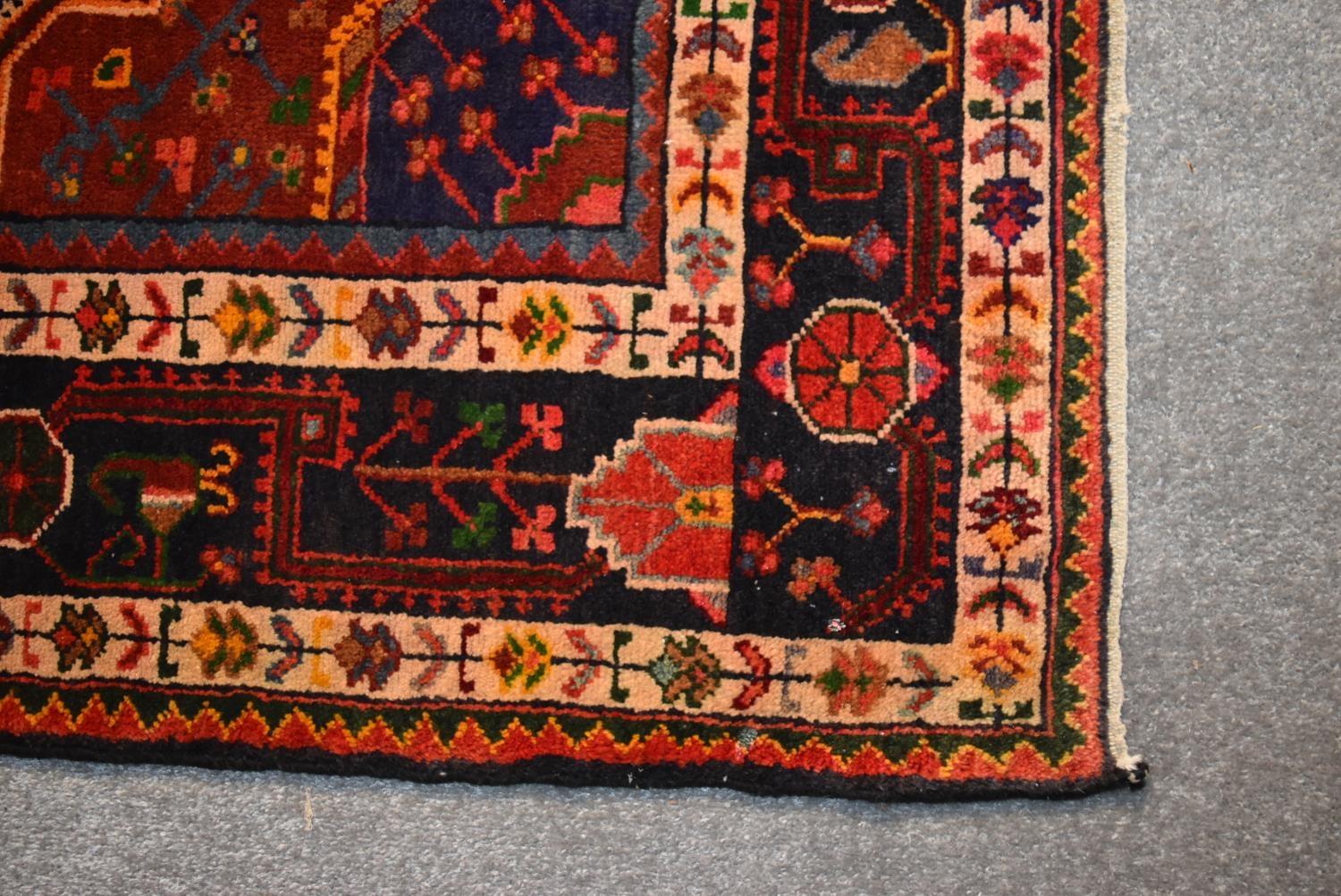 A Persian Nahavand rug with central pendant medallion on a rouge field with meandering vine - Image 3 of 4