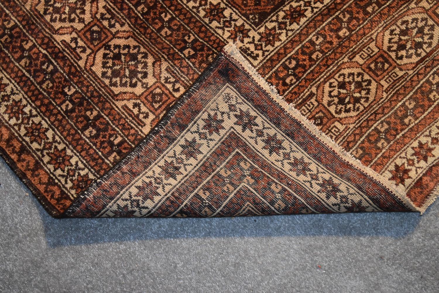 A Turkoman carpet with repeating gul moifs on a chocolate ground contained within stylised floral - Image 3 of 3
