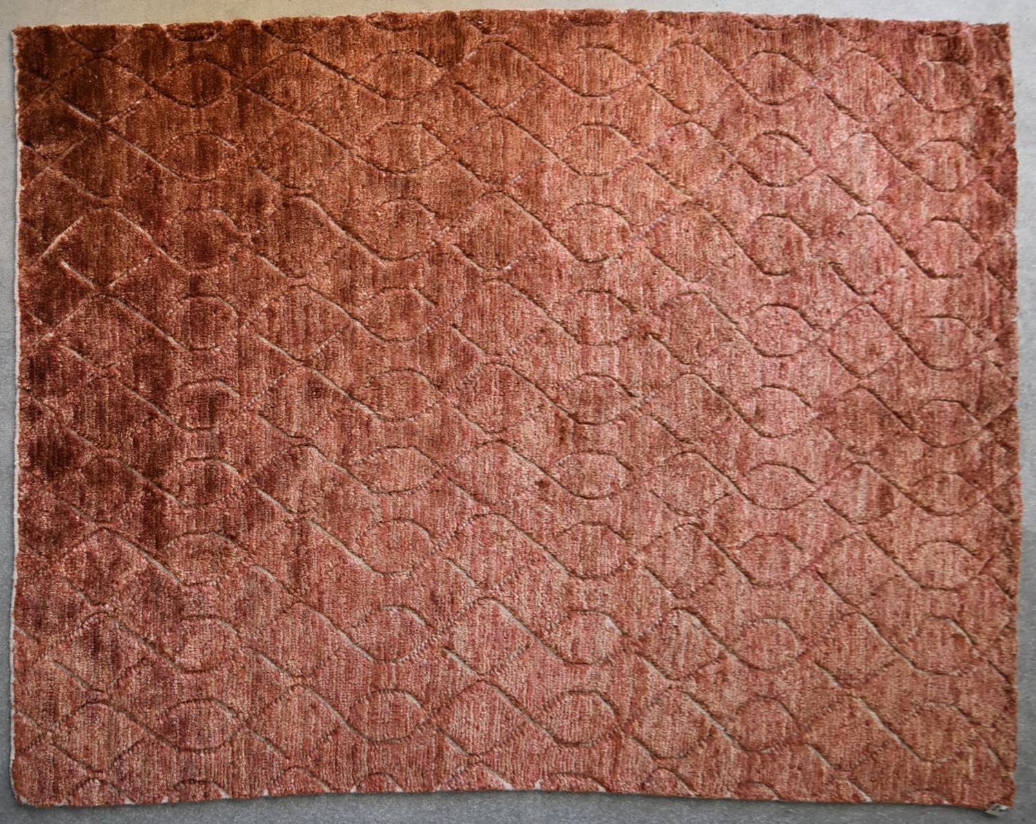 A contemporary carpet with repetitive scrolling interlocking pattern on a rouge field. L.240x206cm