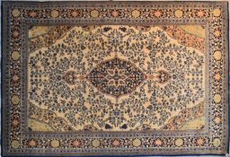 A Qum design carpet with a triple pole medallion and repeating spandrels on a cream ground contained