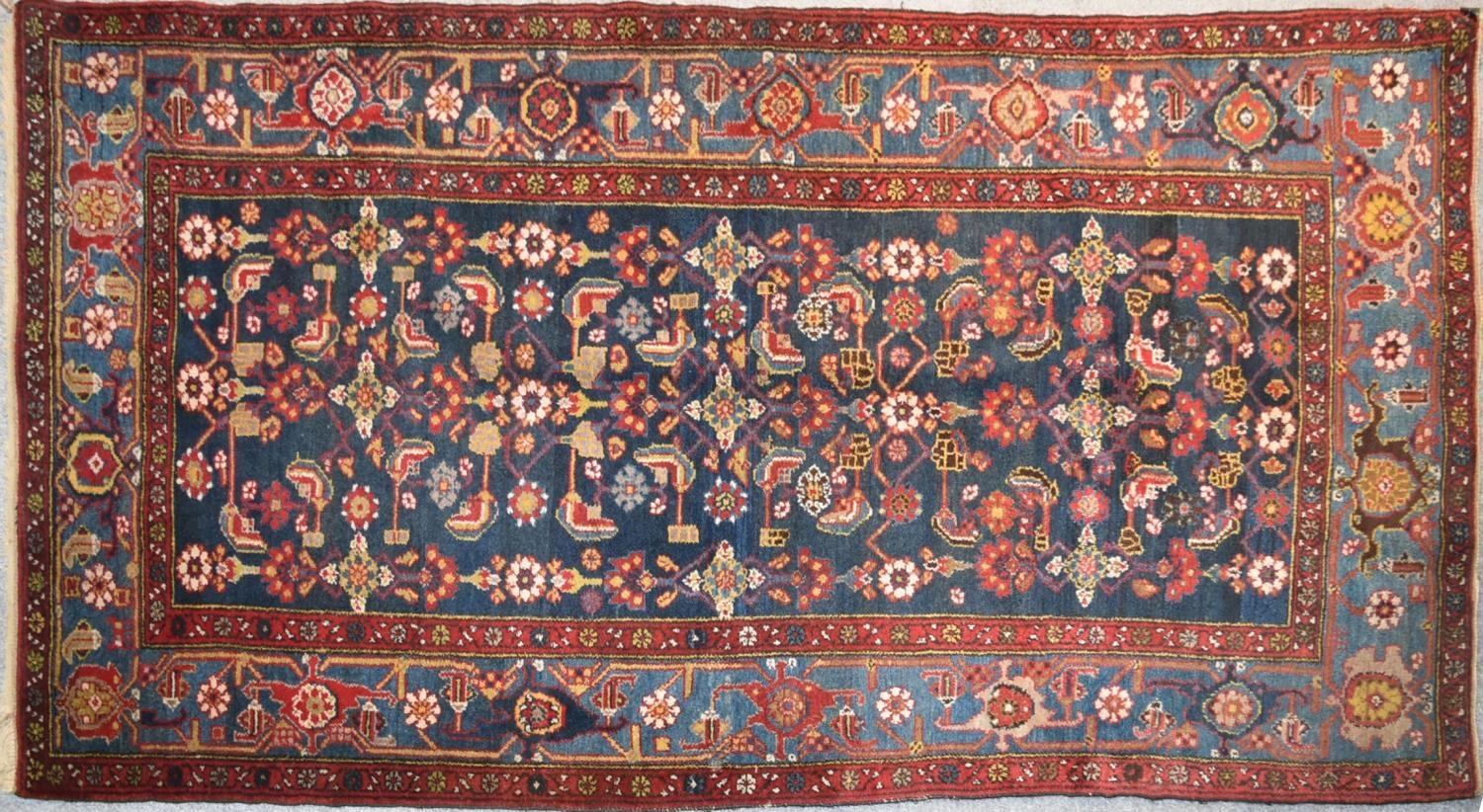 A Persian rug with complete floral and petal motifs on a midnight blue ground contained within