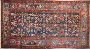 A Persian rug with complete floral and petal motifs on a midnight blue ground contained within