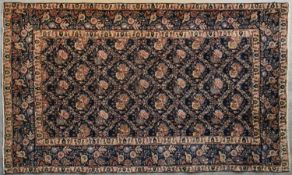A Persian Tabriz finished with repeating floral pattern on a midnight blue ground within ivory