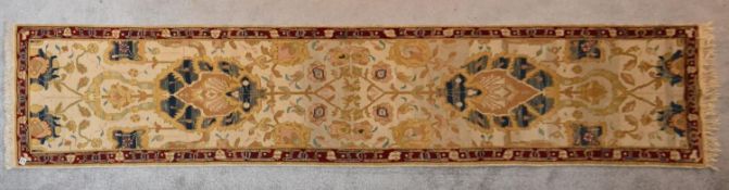 An Agra runner with central palmettes and scrolling floral design on a cream ground within a