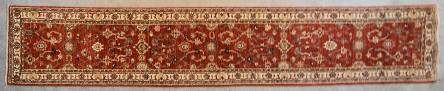 A Ziegler runner with allover scrolling floral design on a deep red field. L.335x60cm