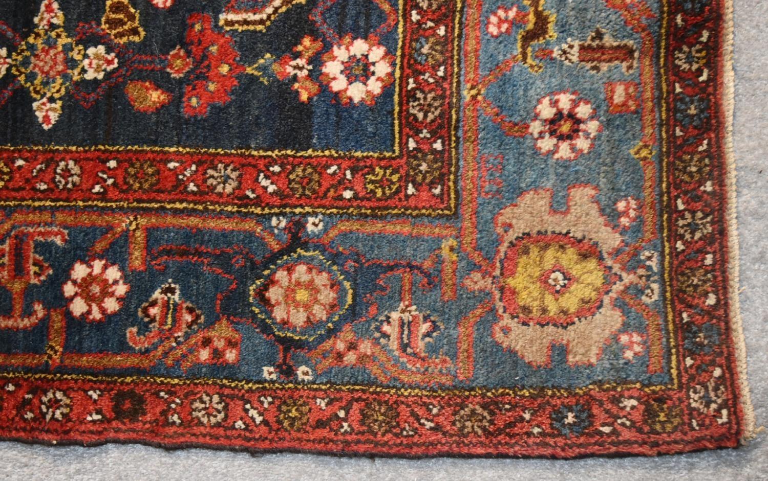 A Persian rug with complete floral and petal motifs on a midnight blue ground contained within - Image 3 of 4