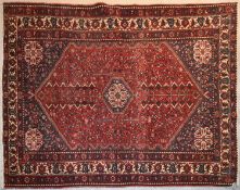 A Persian rug with gul medallion and central lozenge on a rouge field contained within stylised