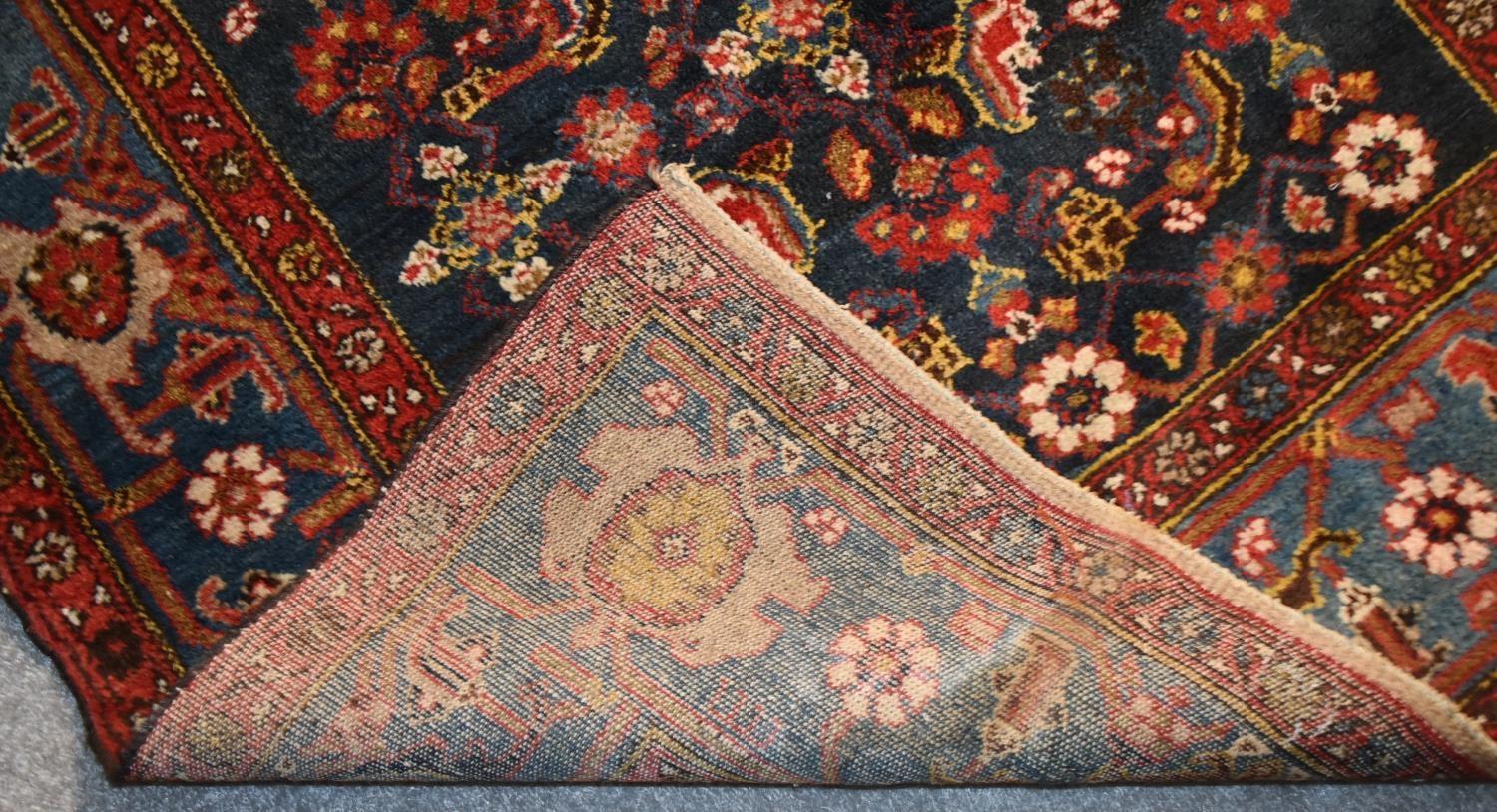 A Persian rug with complete floral and petal motifs on a midnight blue ground contained within - Image 4 of 4
