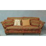 A 20th century two seater sofa in burgundy upholstery with gold highlighted Egyptian motifs on