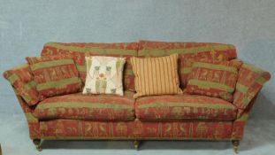 A 20th century two seater sofa in burgundy upholstery with gold highlighted Egyptian motifs on
