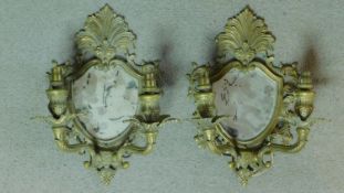 A pair of mid century vintage brass girandoles with twin branches, Rococo cresting and shaped glass.