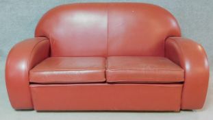 An Art Deco style two seater sofa in burgundy leather upholstery together with the matching stool.