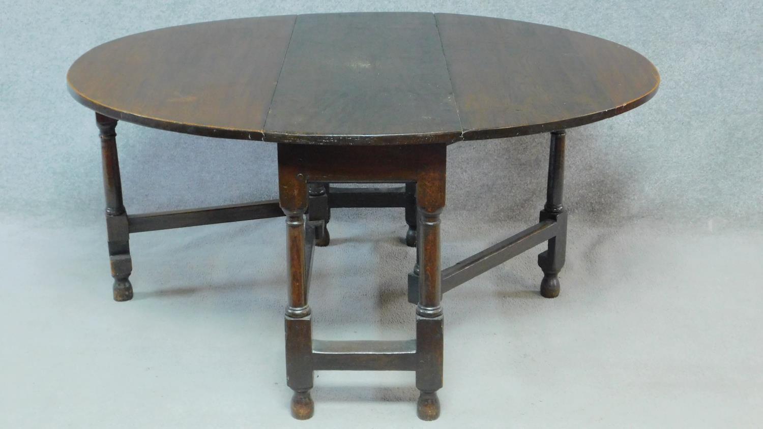 An antique country oak drop flap dining table with gateleg action. H.72 W.147 D.125cm