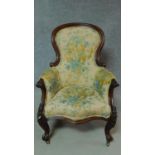 A Victorian mahogany framed armchair in floral upholstery on cabriole supports. H.107cm