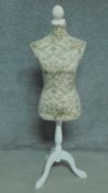 A mannequin on painted tripod base in a floral padded textile. H.134cm