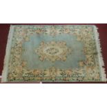 A Chinese woollen carpet with central floral medallion on pale blue ground and floral borders.