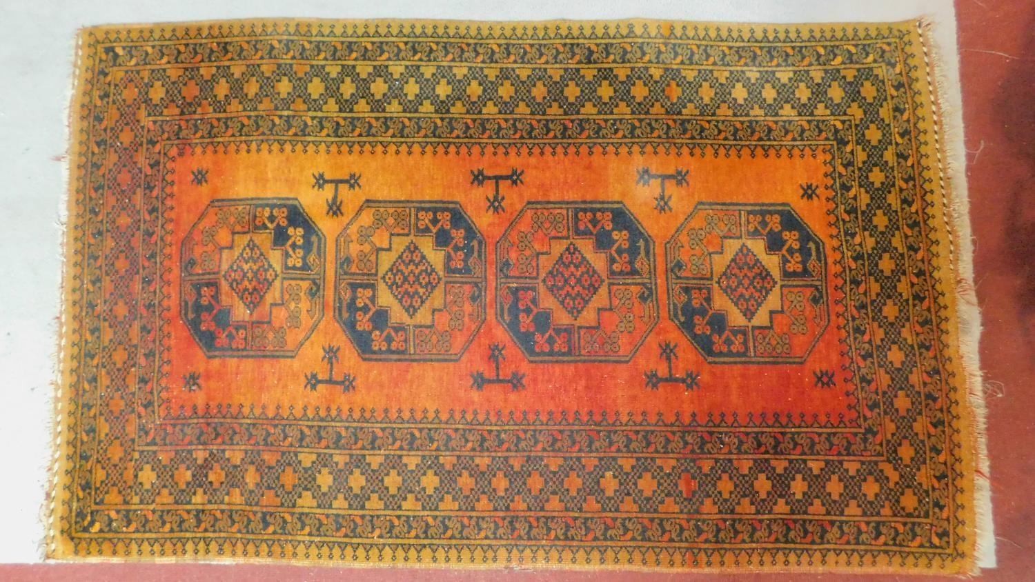 A Shirvan rug with repeating ersur gul medallions on terracotta ground within stylised geometric