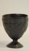 An antique carved coconut chalice, carved with four cartouches, two with tropical flowers, an anchor