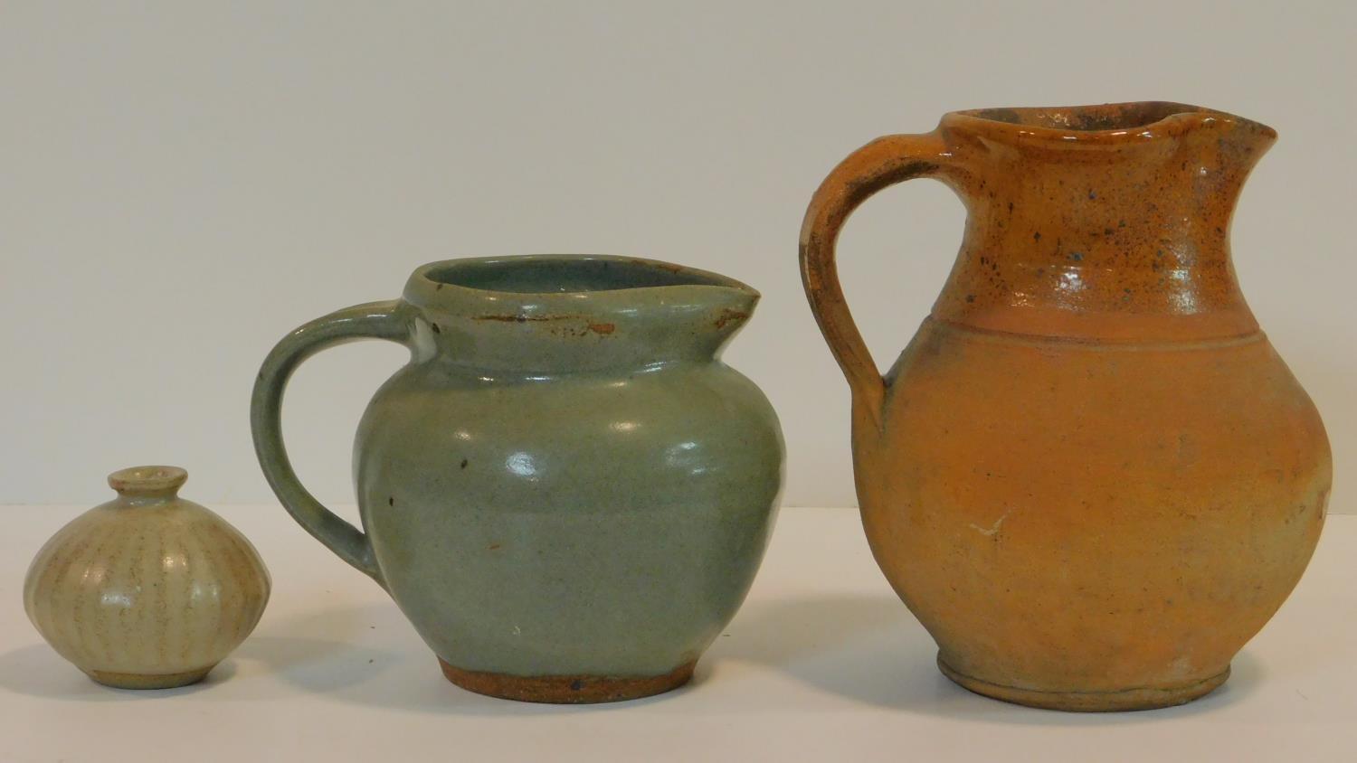 Three glazed studio pottery pieces. Including a glazed jug with pale green glaze and makers mark