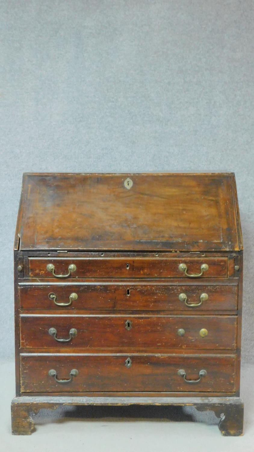 A Georgian mahogany bureau with fall front revealing fitted interior above four graduated drawers on