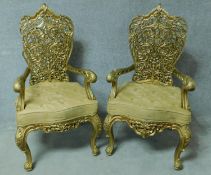 A pair of later painted Burmese teak open armchairs with intricately carved floral backs in lemon