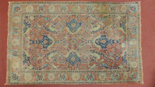 A Persian rug with allover scrolling foliate decoration on a rouge ground contained within