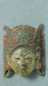 An antique painted carved and gilded Oriental mask with traditional headdress. 24x20cm