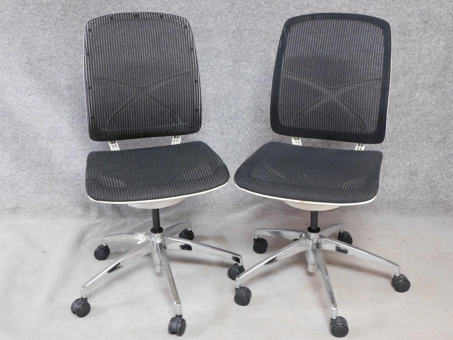 A pair of contemporary swivelling adjustable office desk chairs with mesh backs and seats. H.100