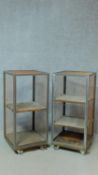 A pair of metal framed industrial style trolleys with adjustable teak shelving and incised makers or