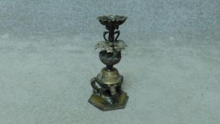 An Oriental bronze candle holder with three storks holding a lotus flower, sitting on an engraved