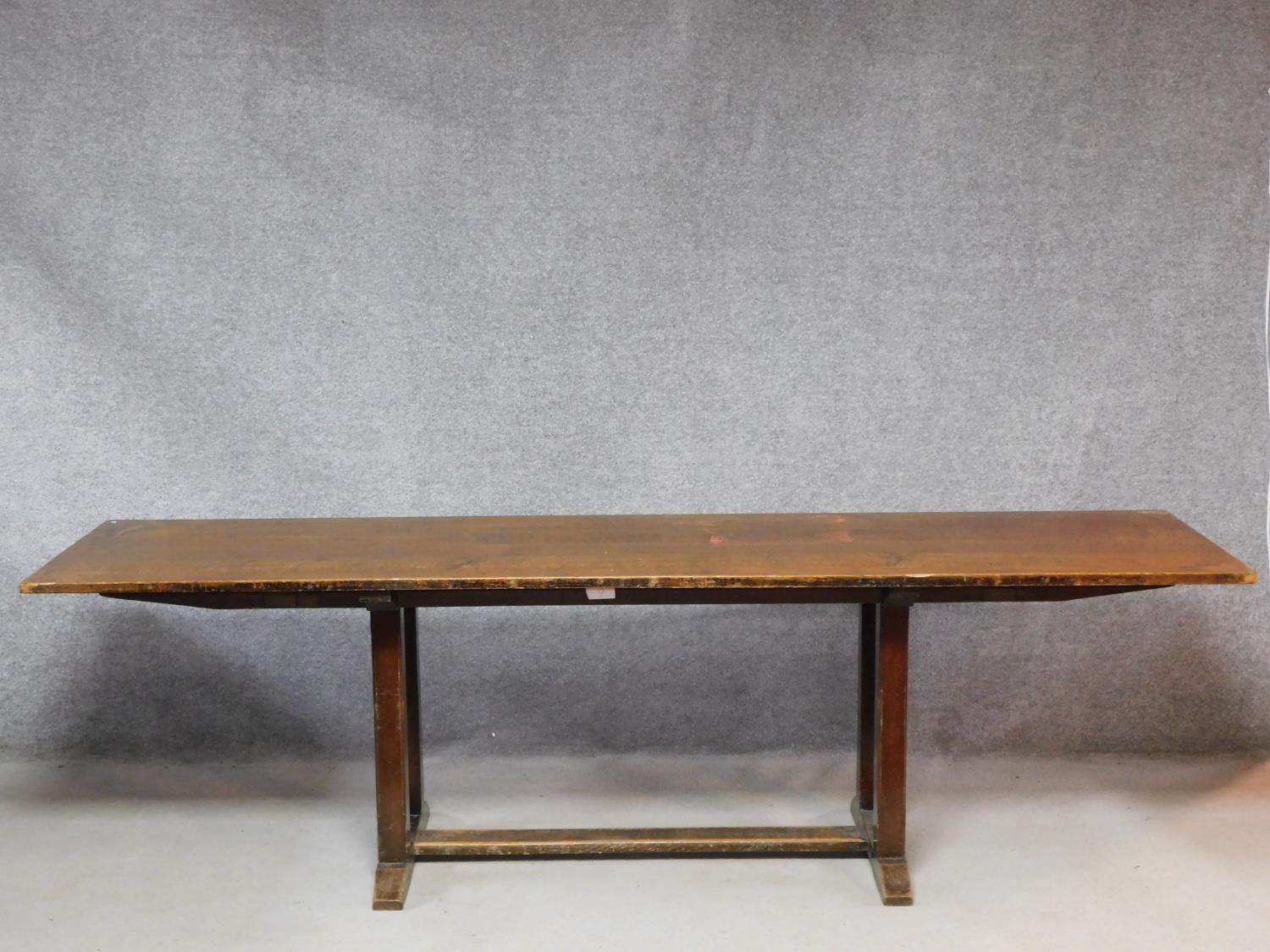 An oak refectory style dining table on stretchered chamfered square section supports on a platform