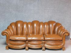 An Italian carved walnut framed Arredo style sofa in tan leather scalloped upholstery. H.86 W.226