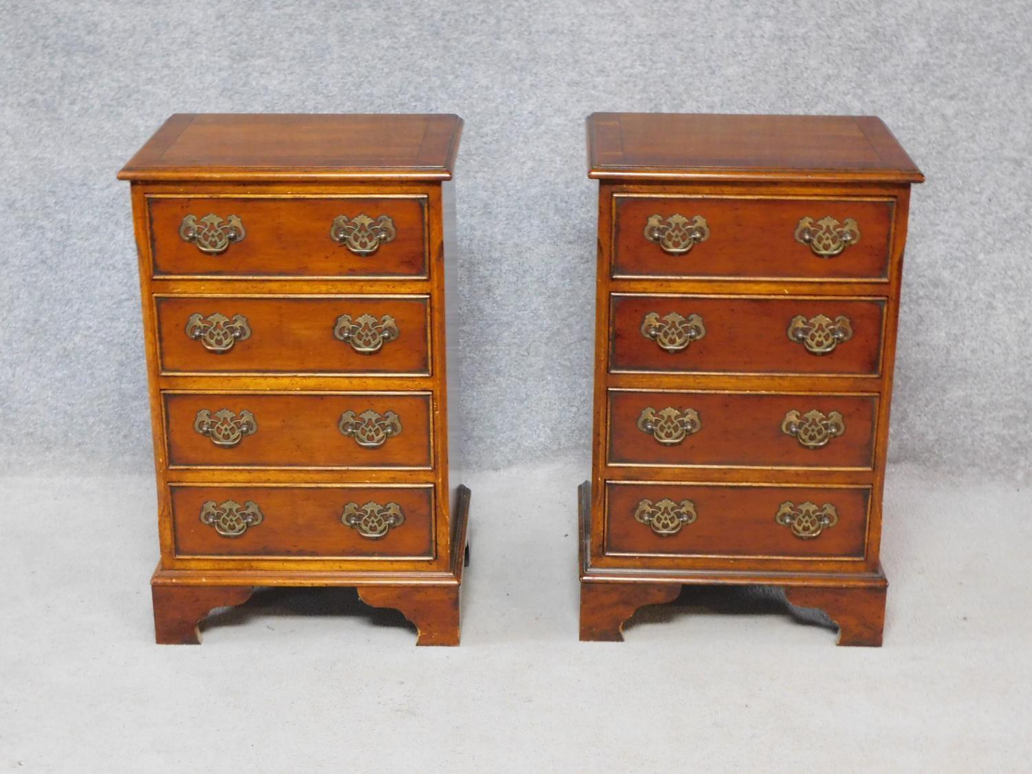 A pair of Georgian style yew wood and crossbanded bedside chests of four drawers on bracket feet.