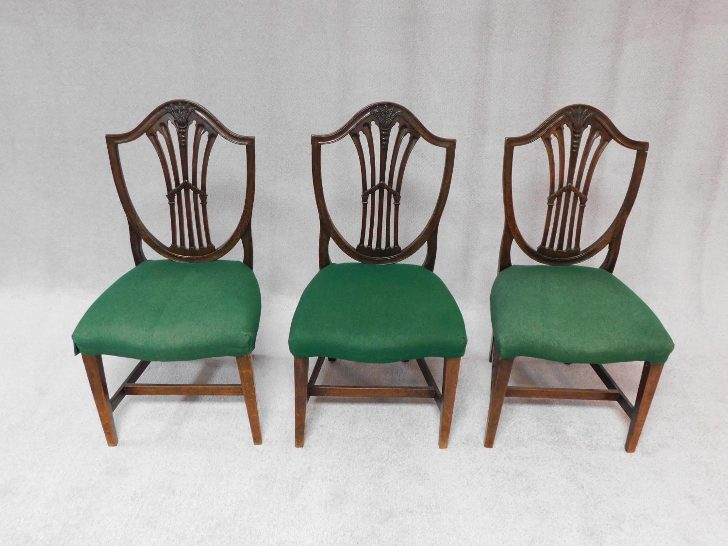 A set of three 19th century mahogany dining chairs with Hepplewhite style shield shaped pierced